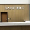 Dimensional Letters 7 Healthcare facility atrium reception area with large white dimensional letter logo sign on a warm wood plank wall above a marble reception desk